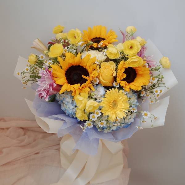 Bouquet of sunflowers, yellow roses, and pastel flowers wrapped in paper