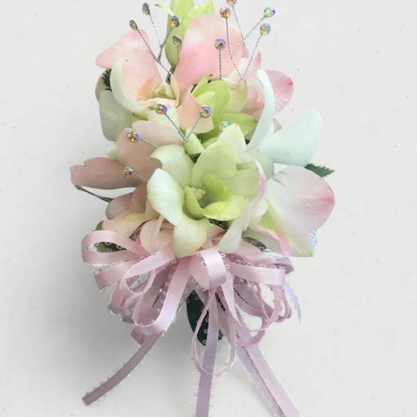 Small pastel floral corsage with pink and green petals and a ribbon bow