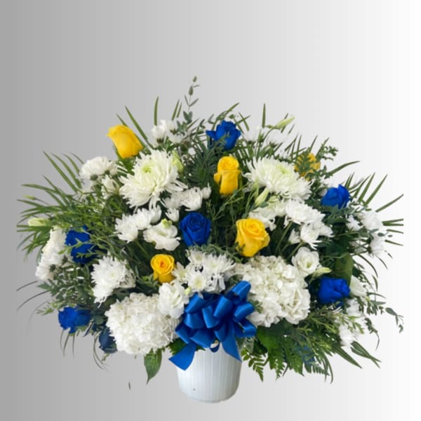 White and blue floral arrangement with yellow roses in a white vase