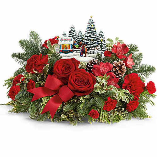 Red roses and carnations arranged with a ribbon and holiday village centerpiece