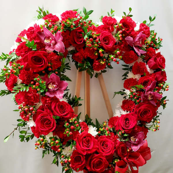 Heart-shaped wreath of red roses and carnations with pink orchids