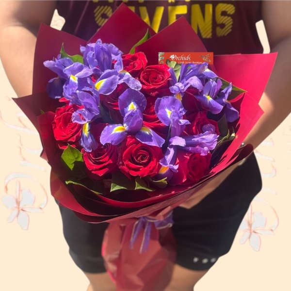 Bouquet of red roses and purple irises wrapped in burgundy paper