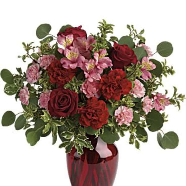 Red and pink floral arrangement in a red glass vase