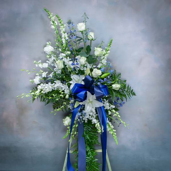 Tall white and blue floral standing spray with a blue ribbon