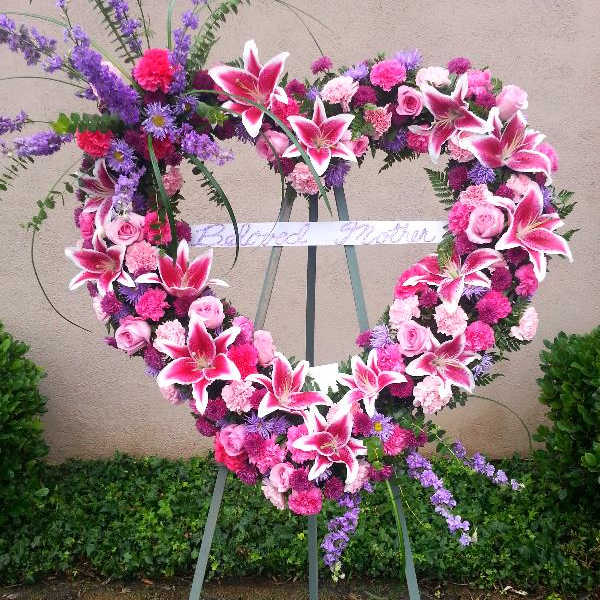 Heart-shaped floral wreath on an easel with pink and purple flowers