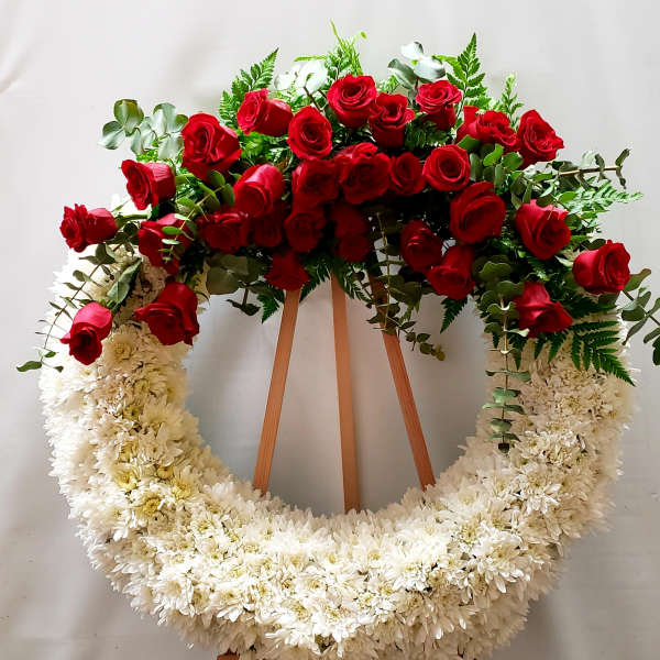 Red roses and white chrysanthemum wreath on a wooden easel