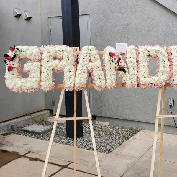 Floral sign spelling "GRANDMA" on easels with white and pink flowers