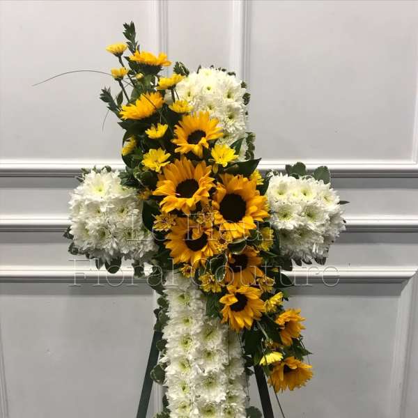 Cross-shaped floral tribute with yellow sunflowers and white chrysanthemums