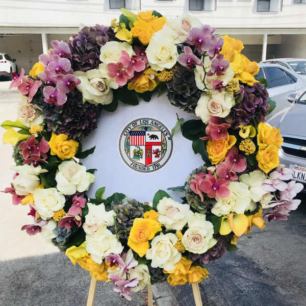 Large floral wreath with roses, orchids, and hydrangeas around a city seal
