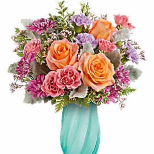 Bouquet of peach roses and pink mixed flowers in a turquoise vase