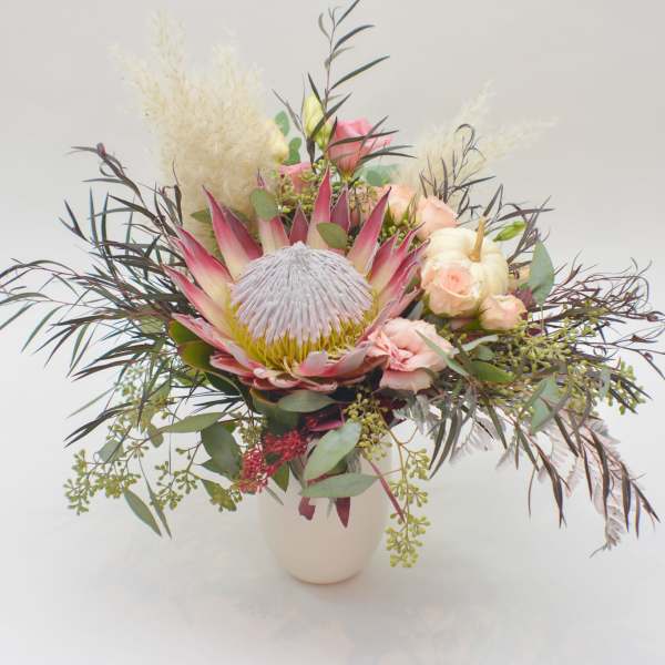 Mixed bouquet with a large pink protea in a white vase
