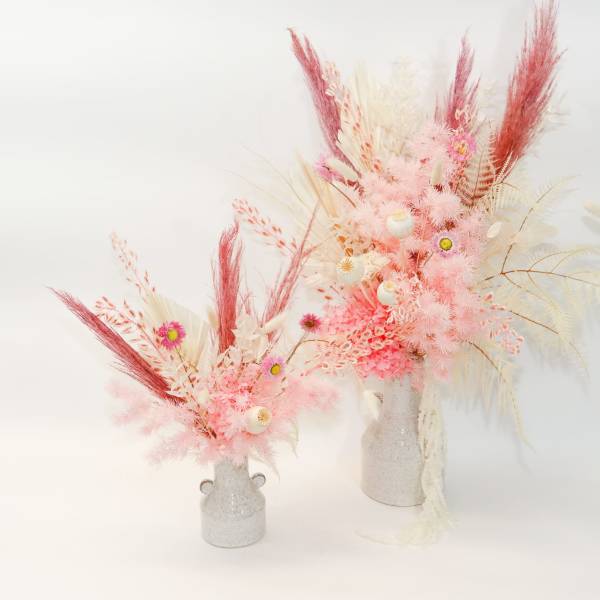 Two pink and white dried floral arrangements in small vases