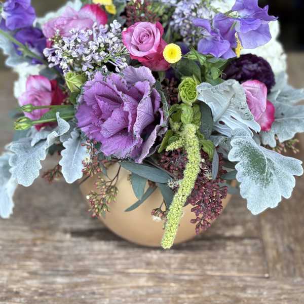 Mixed purple and pink bouquet in a tan vase