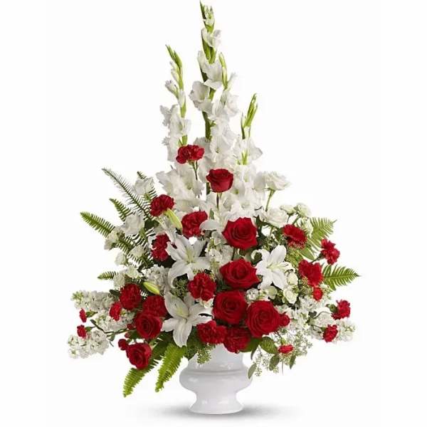 Tall red and white floral arrangement in a white pedestal vase