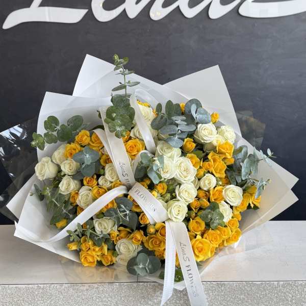 Bouquet of yellow and white roses with eucalyptus in white wrap