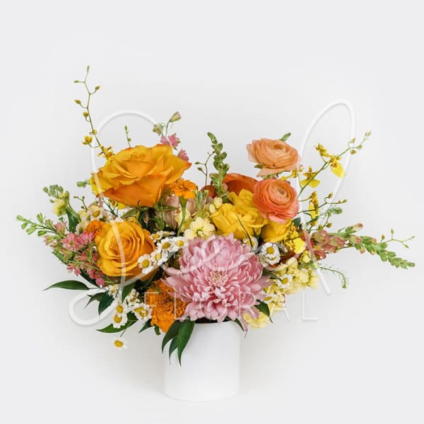 Vibrant arrangement of yellow and orange roses with a pink chrysanthemum in a white vase