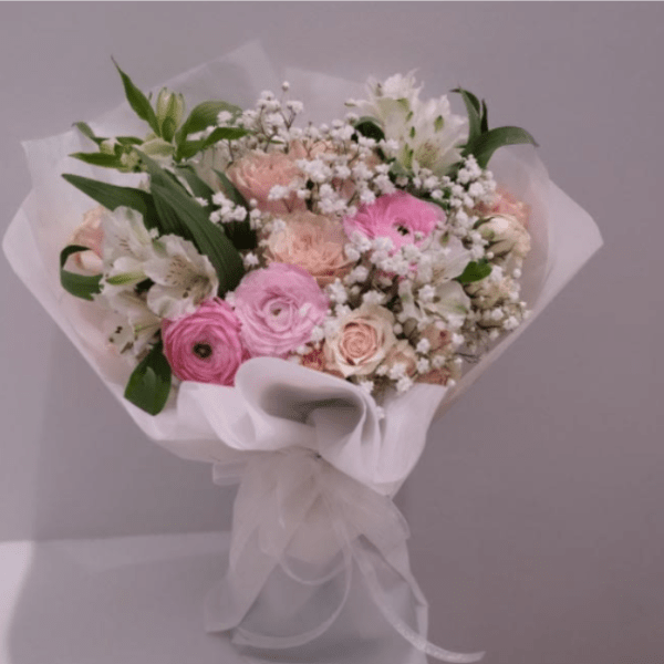Pink and white mixed bouquet wrapped in white paper with a ribbon