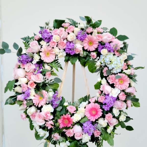 Heart-shaped floral wreath with pink, white, and purple flowers on an easel