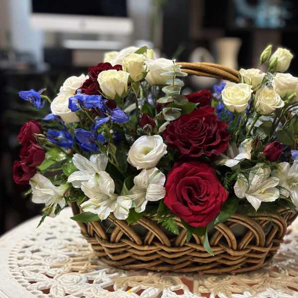 Basket arrangement of red and white roses with blue flowers