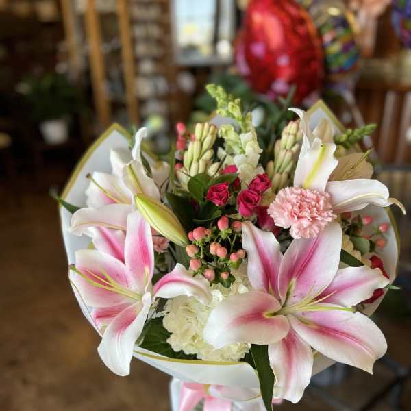 Pink and white lily bouquet with roses and carnations in a glass vase