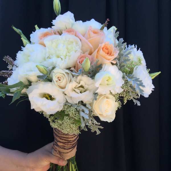 Handheld bouquet of white and peach roses with white blooms