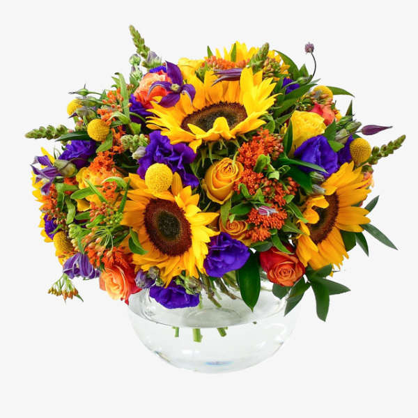Bright mixed bouquet with sunflowers, roses, and purple blooms in a glass bowl vase