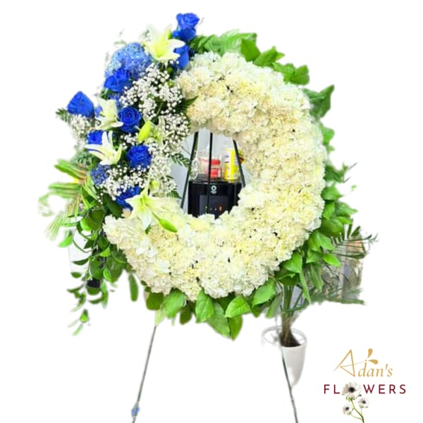 Large floral wreath on a stand with white and blue flowers