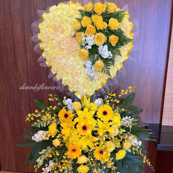 Heart-shaped yellow floral tribute above a mixed yellow standing spray