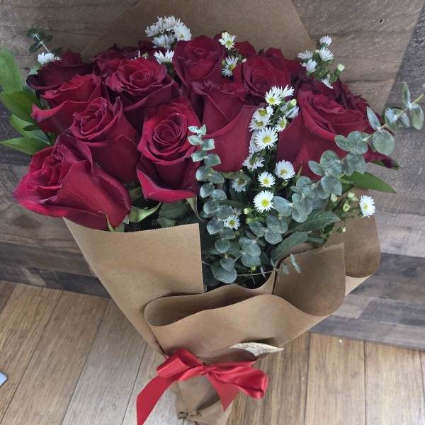 Bouquet of red roses with small white daisies wrapped in brown paper