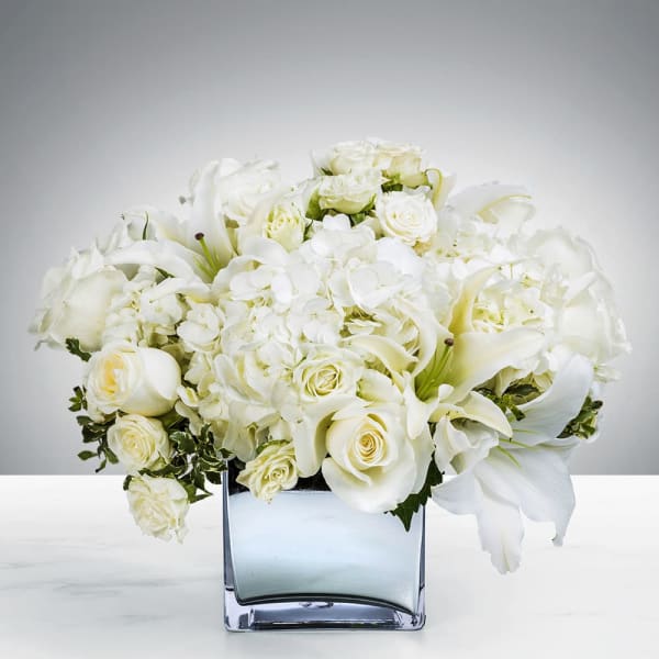 White roses and calla lilies arranged in a square glass vase