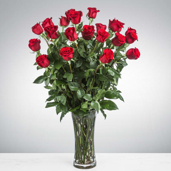 Tall bouquet of red roses in a clear glass vase