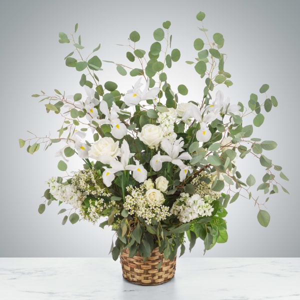 White floral arrangement in a woven basket with airy eucalyptus branches
