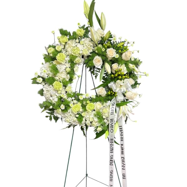 White and green funeral wreath on a stand with ribbon