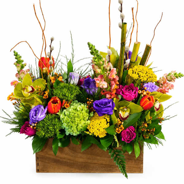 Colorful mixed flower arrangement in a wooden box with tall branches