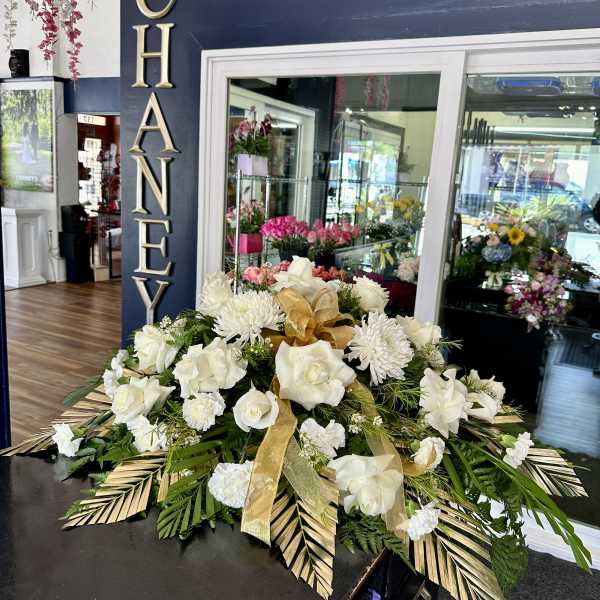 White floral arrangement with roses and chrysanthemums, accented by gold ribbon