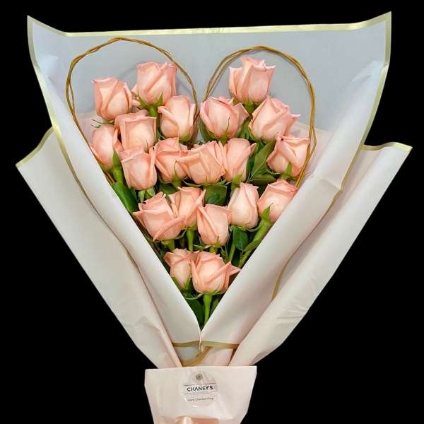 Bouquet of pale pink roses wrapped in white paper with a satin bow