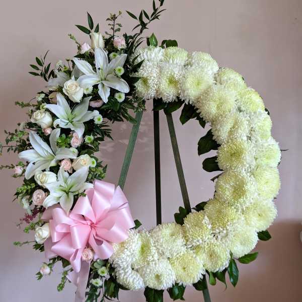 Heart-shaped floral wreath with white flowers and a pink ribbon bow
