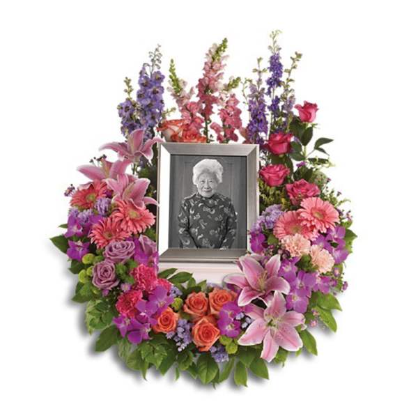 Sympathy wreath of pink, purple, and orange flowers around a framed photo