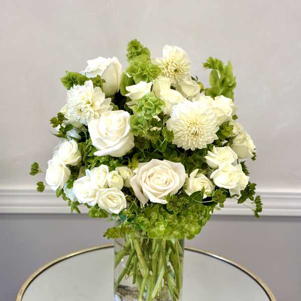 White roses and dahlias arranged in a clear glass vase