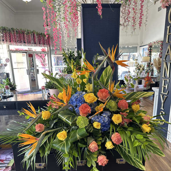 Large tropical floral arrangement with birds of paradise, roses, hydrangeas, and greenery