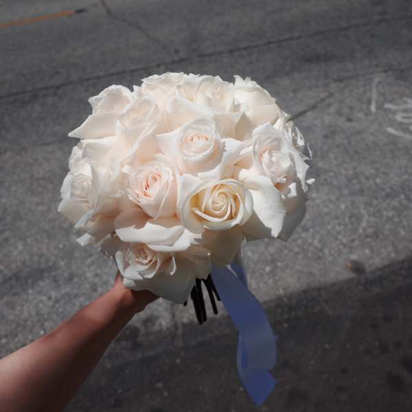 White rose bouquet with a blue ribbon tied around the stems