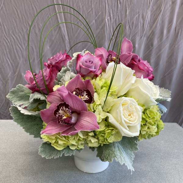 Pink and white floral arrangement in a white vase with arched stems
