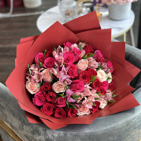 Bouquet of pink and red roses with pale pink alstroemeria in red wrap
