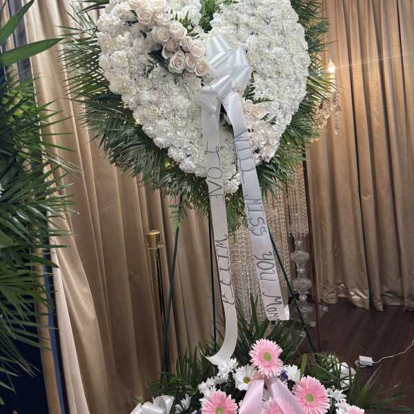 Heart-shaped white floral standing spray with ribbon streamers