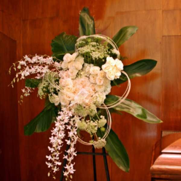 Standing floral spray with pale pink and white blooms on a black easel