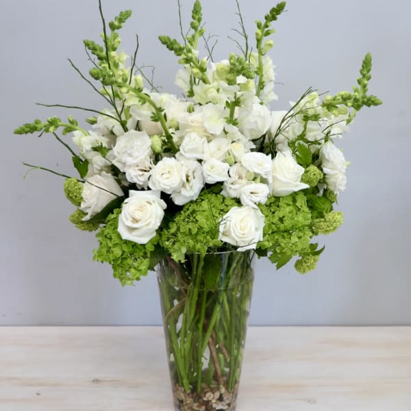 White roses and snapdragons in a tall glass vase