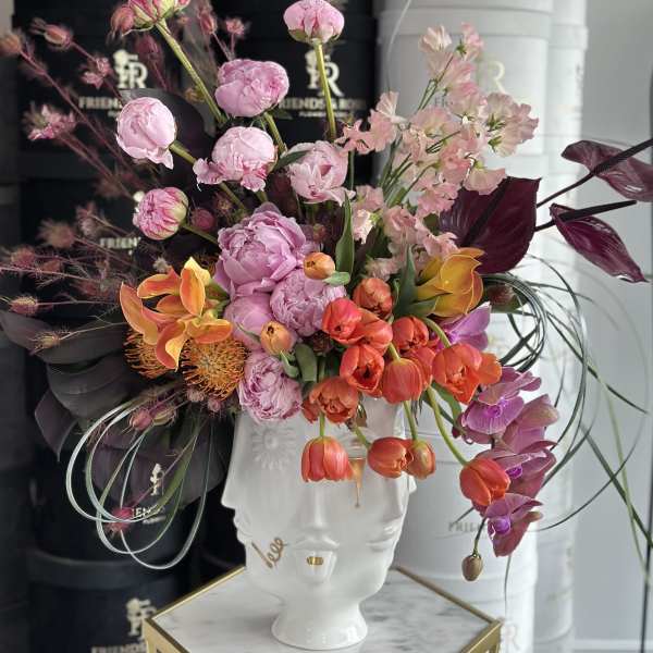 Colorful floral arrangement in a white face-shaped vase