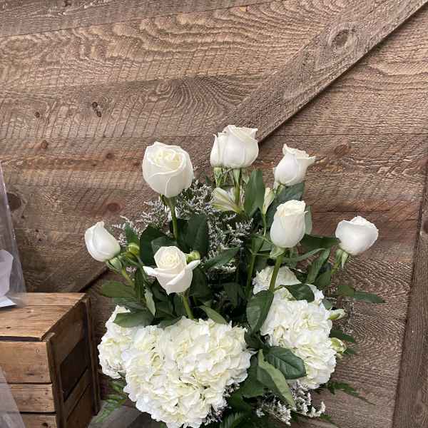 White roses and hydrangeas arranged in a glass vase