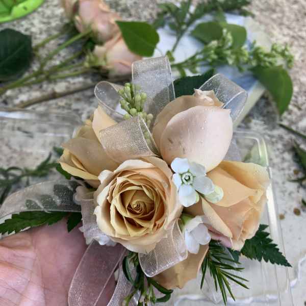 Small bouquet of peach roses with ribbon and greenery