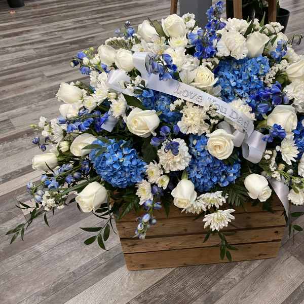 Blue and white floral arrangement in a wooden box with a ribbon